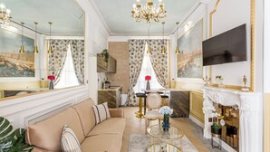 Un salon luxueux avec un canapé beige, une table basse en verre, une cheminée et un téléviseur.