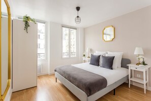 Un dormitorio moderno con una cama grande, mesitas de noche, un espejo y una planta colgante.