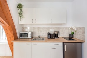 Eine moderne Küche mit weißen Schränken, einer Mikrowelle, einer Kaffeemaschine und einem Spülbecken.
