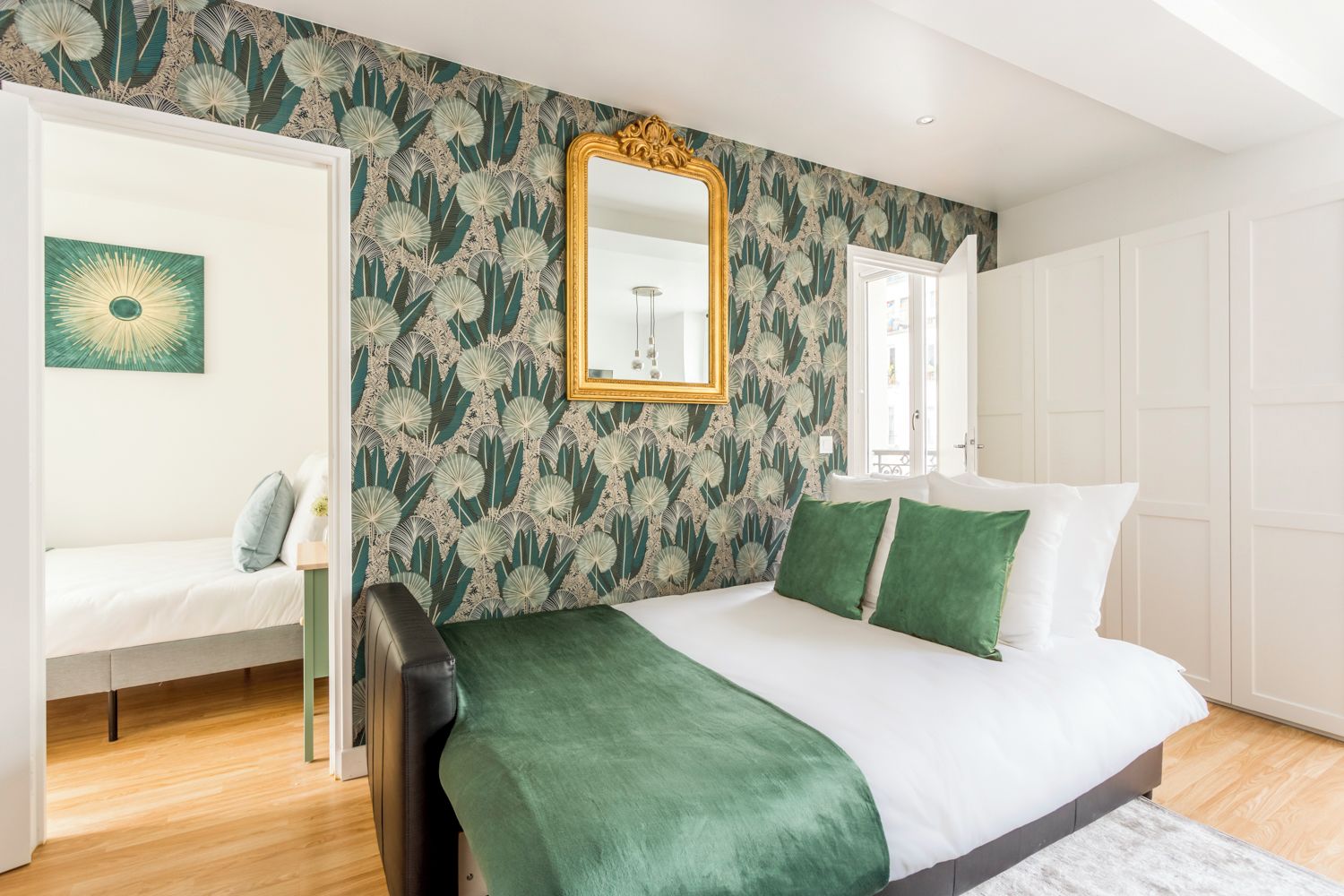 A bedroom with a bed, a mirror, and a wall with a floral pattern.