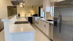 Una cucina moderna con mobili bianchi, un frigorifero in acciaio inox e un'isola centrale.