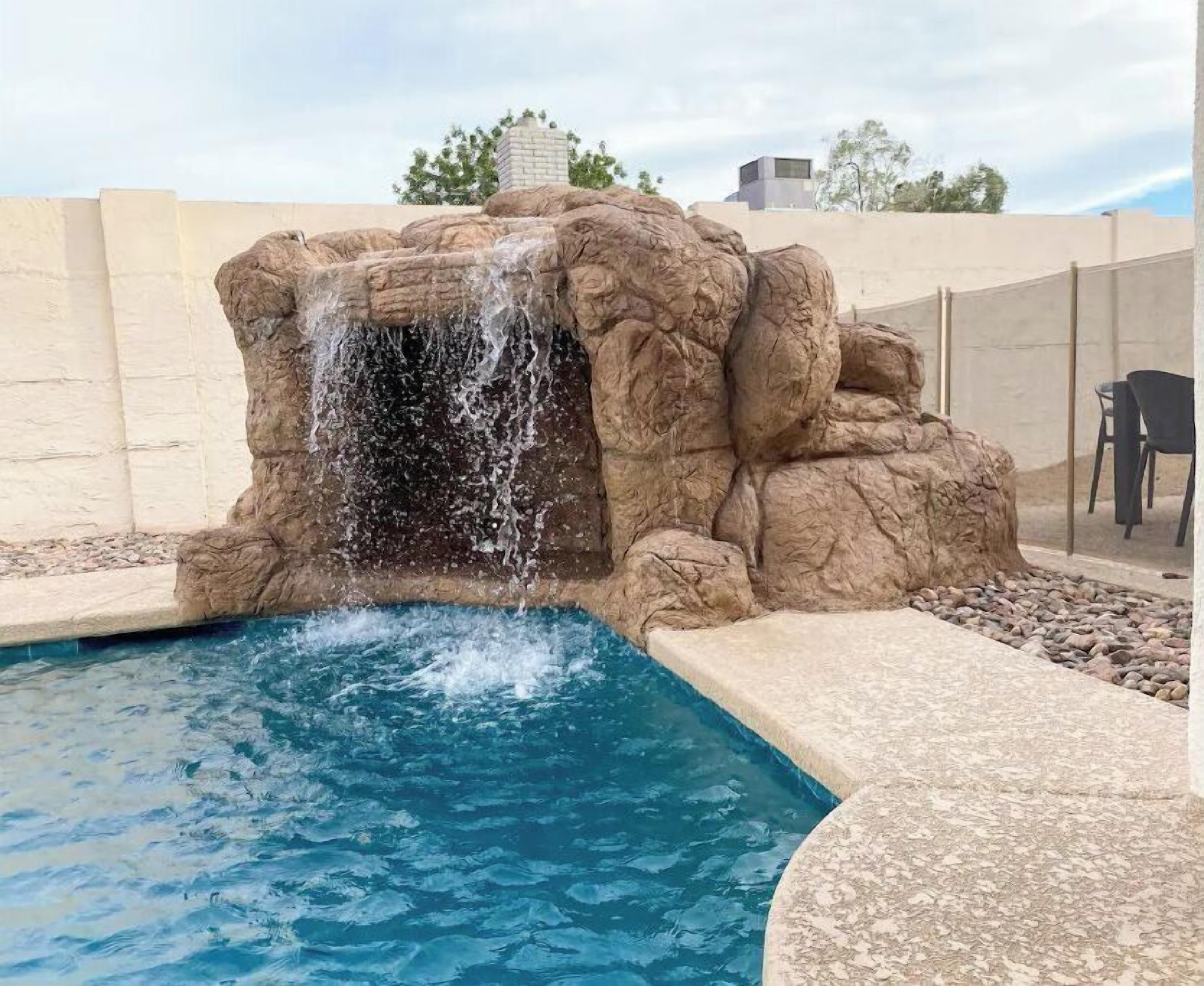 Una piscina con una cascada artificial de rocas.