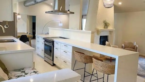 Una cucina moderna con mobili bianchi, una cappa in acciaio inossidabile e un'isola centrale con sgabelli.