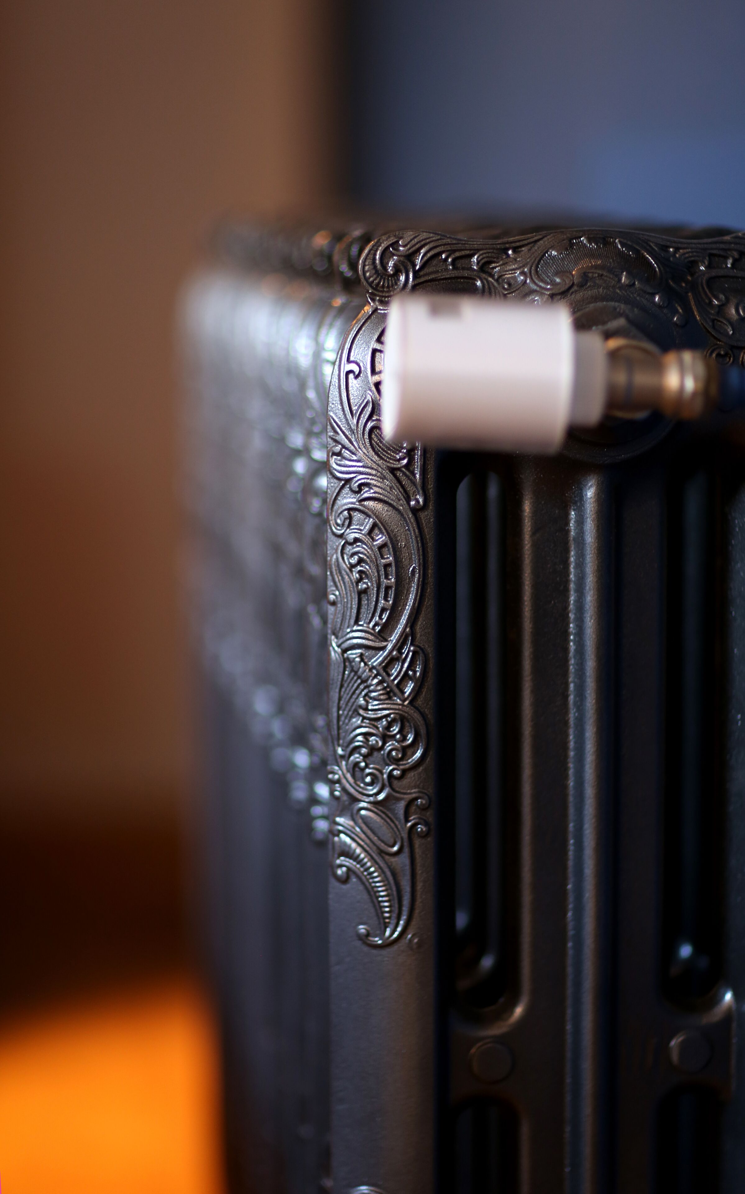A close-up of a radiator with intricate metalwork and a white pipe.