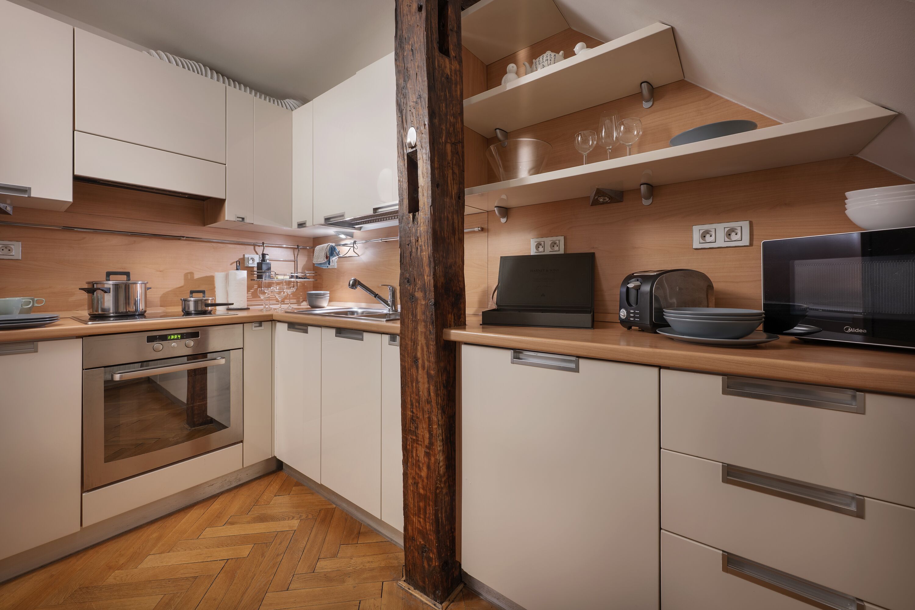 Eine moderne Küche mit Holzschränken, einem Einbauofen, einer Mikrowelle und einer Holzarbeitsplatte.