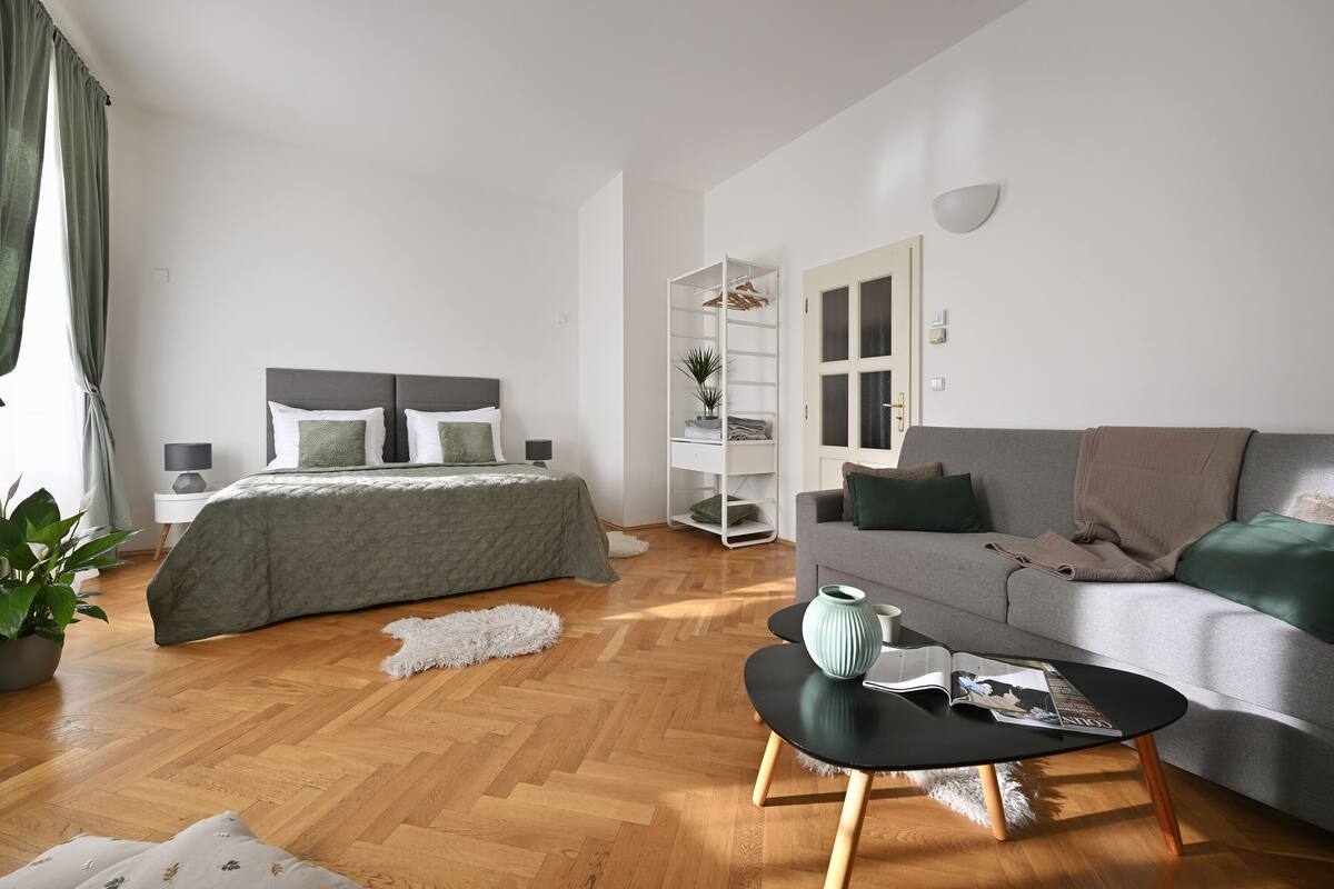 Un dormitorio moderno con cama, mesita de noche y un sofá gris.