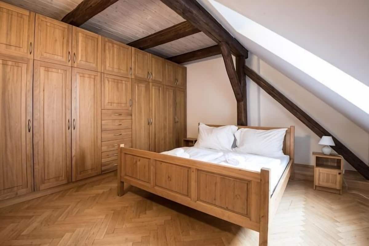 Un dormitorio con cama de madera, armario empotrado y techo inclinado.