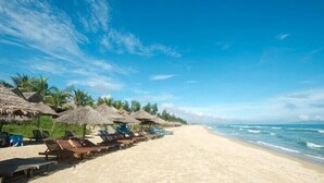 A beach with thatched umbrellas and lounge chairs along the shore. - An Bang Garden - 4BR pool villa- 3 mins walk to An Bang beach. (Thành phố Hội An)