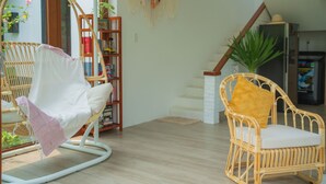 A room with a wicker chair, a bookshelf, and a staircase. - An Bang Garden - 4BR pool villa- 3 mins walk to An Bang beach. (Thành phố Hội An)