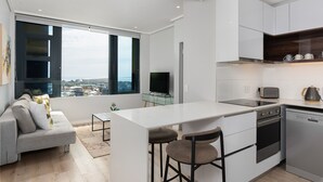 Et moderne køkken med en central ø, indbyggede hårde hvidevarer og et stort vindue med udsigt over byen.
