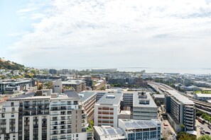 A cityscape with modern buildings, a highway, and a body of water in the distance.