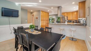 Una cocina moderna con armarios de madera, una campana extractora de acero inoxidable y una isla integrada con taburetes de bar.