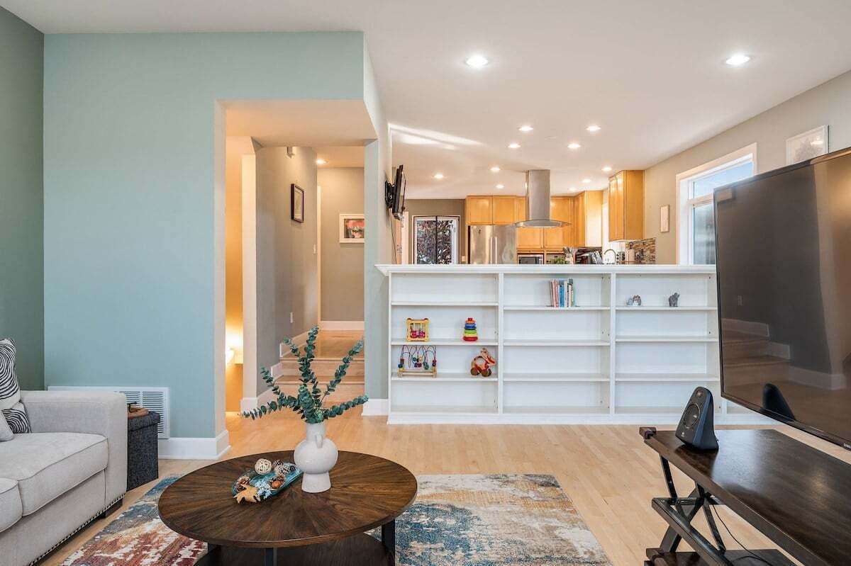 Un salon moderne avec un canapé, une table basse et une bibliothèque remplie de jouets pour enfants.
