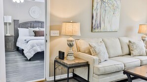 A hotel room with a bed, a sofa, a side table with a lamp, and a painting on the wall. - 2 King Bed Master Suites and 1/2 Mile from Chief  Ladiga Trails and Elwell Park (Weaver)