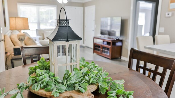 A dining table with a white lantern and green foliage centerpiece. - 2 King Bed Master Suites and 1/2 Mile from Chief  Ladiga Trails and Elwell Park (Weaver)