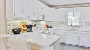 A modern kitchen with white cabinetry, a marble countertop, and a built-in oven. - 2 King Bed Master Suites and 1/2 Mile from Chief  Ladiga Trails and Elwell Park (Weaver)