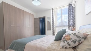 A bedroom with a bed, a wardrobe, a window with curtains, and a ceiling light. - ★★Modern And Cozy Apartment ,Close to The Sea ★★3 (San Pawl il-Baħar, Malta)