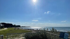 A coastal view with a clear sky, a pathway leading to the beach, and a signboard. - Parrwang Rest - Renovated cosy unit in a Serene Location. (Portarlington)