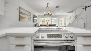 A modern kitchen with a central island, stainless steel appliances, and a chandelier. - Overlooking the Lagoon and Pool (Key Largo)