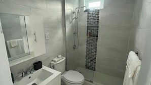 A modern bathroom with a white sink, toilet, and shower. - Ocean Side PR (Carolina)