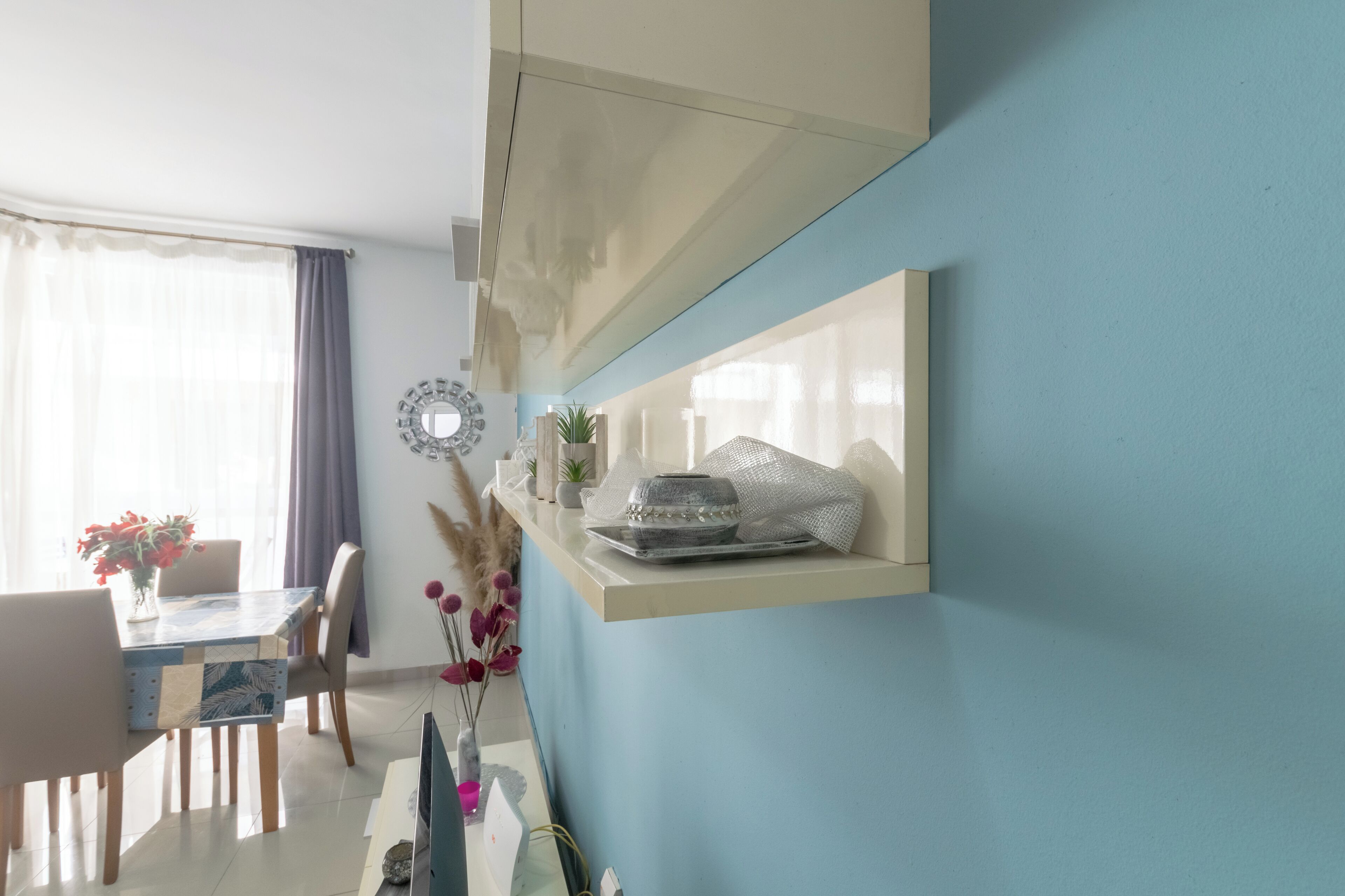 A modern dining area with a table, chairs, and a decorative mirror on the wall.