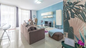 A modern living room with a sofa, a glass coffee table, and a TV. There is a dining area with a table and chairs. - ☆☆Amazing Apartment w/side sea view☆☆ 1 (St. Pauls Bay, Malta)