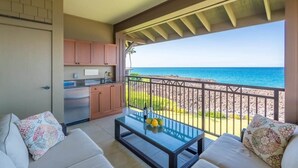 Un balcone con vista sull'oceano, una zona cottura e un angolo salotto con tavolo.