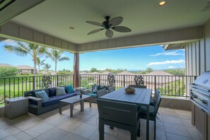 A balcony with a dining area, a sofa, and a grill.