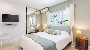 A modern bedroom with a large bed, a television, and a window with curtains. - Villa Anse Vinaigri - Beach on foot 👣 (Le Gosier)
