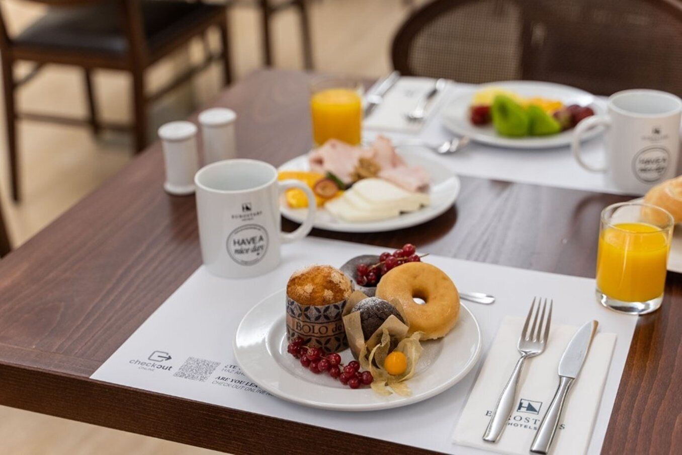 A breakfast setting with a plate of food, a mug, and a glass of orange juice on a table.