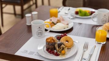 Ein Frühstückstisch mit Speisen, einer Tasse und einem Glas Orangensaft.