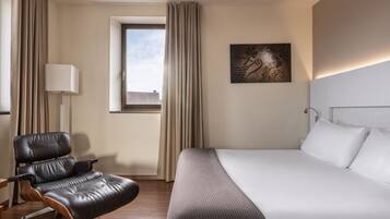 Ein Hotelzimmer mit Bett, Sessel, Fenster und Lampe.