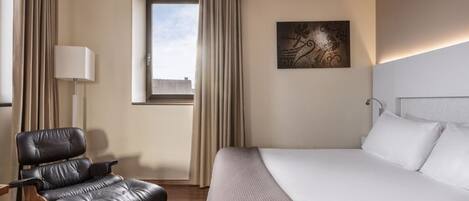 Una habitación de hotel con una cama, una silla, un ventanal y una lámpara.
