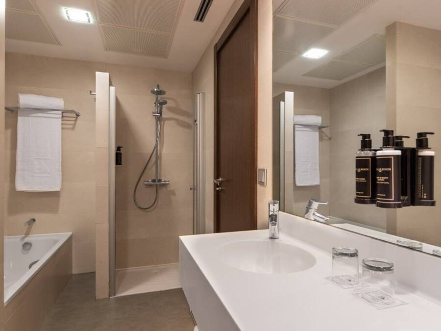 A modern bathroom with a large mirror, a shower, and a bathtub.
