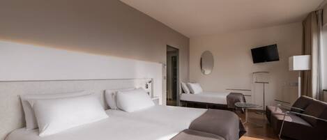 Een hotelkamer met twee bedden, een bureau, een stoel, een televisie en een spiegel.