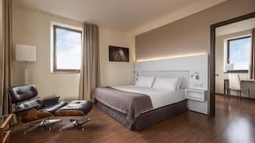 Et moderne hotelværelse med en stor seng, et skrivebord, en læderstol og et stort vindue.