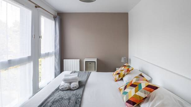 Een moderne hotelkamer met een groot bed, nachtkastje, lamp en uitzicht op het landschap.