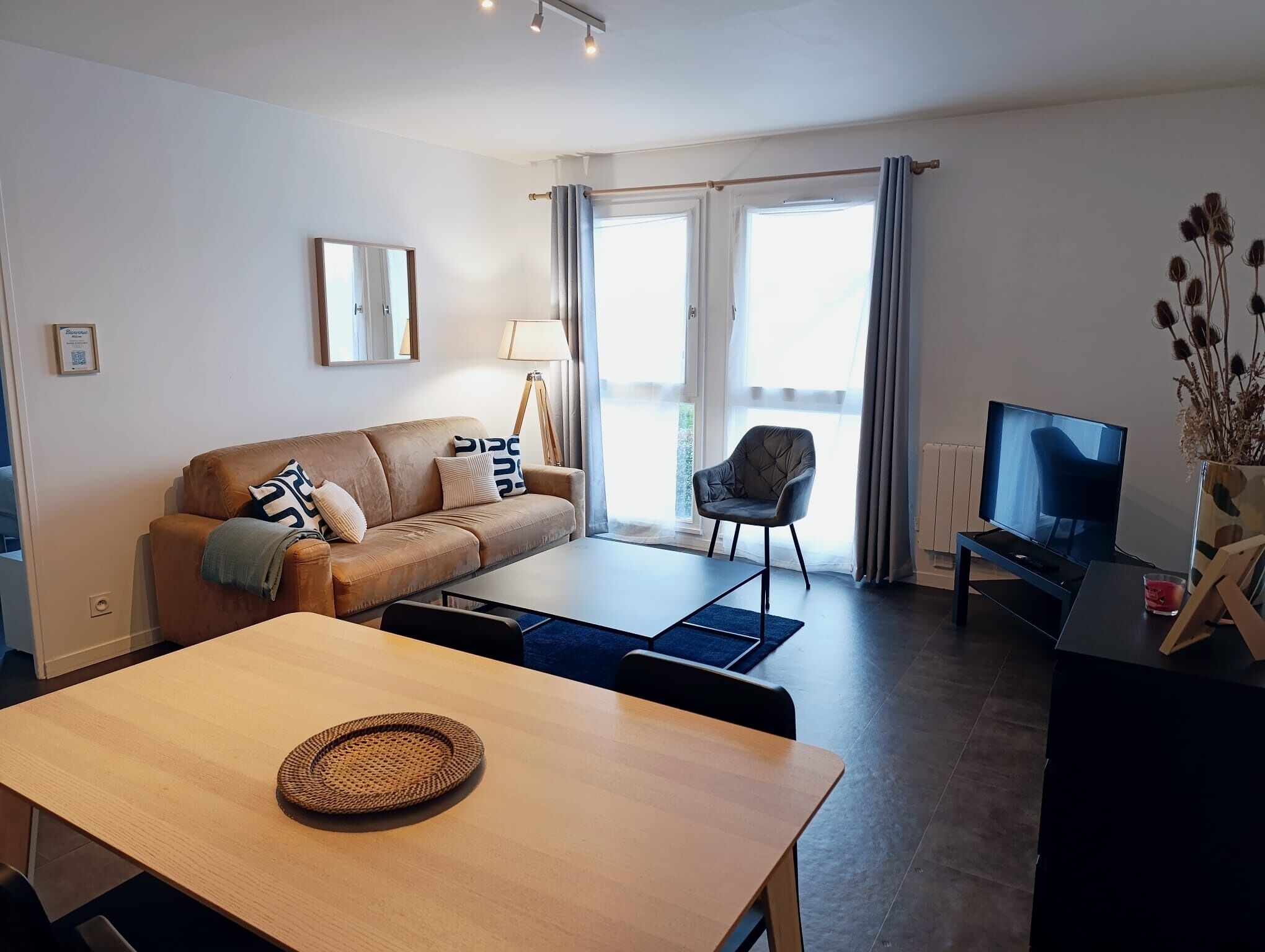 Una sala de estar moderna con un sofá, una mesa de comedor, un televisor y una silla.