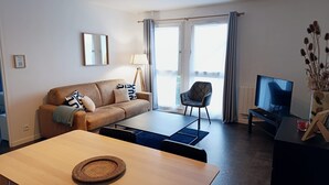 Een moderne woonkamer met een bank, een eettafel, een televisie en een stoel.