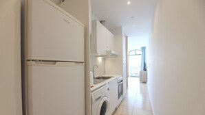 Une cuisine compacte équipée d’un lave-linge, d’un évier et d’un four encastré.