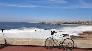 Une plage où l’on aperçoit un vélo et une trottinette électrique garés au bord de l’eau.