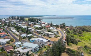 A coastal residential area with houses, roads, and a beach in the background.