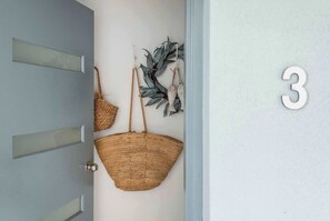 A door with a number '3' on the wall, a woven basket hanging on the door, and a decorative plant on the wall.