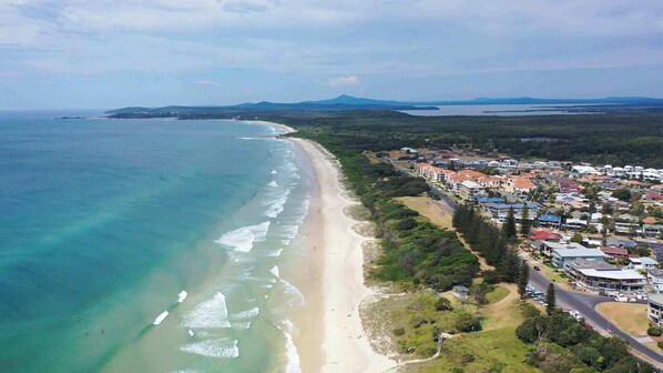 An aerial view of a coastal town with a sandy beach, residential buildings, and a mountain in the background. - La Ronde Three - Oceanstays - Unit 3 (Yamba)