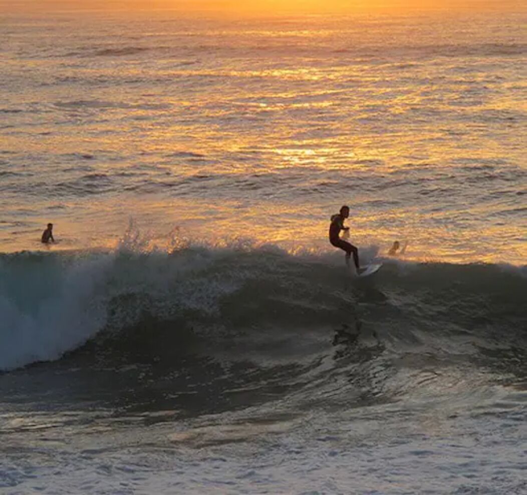 Un surfeur chevauchant une vague au coucher du soleil.