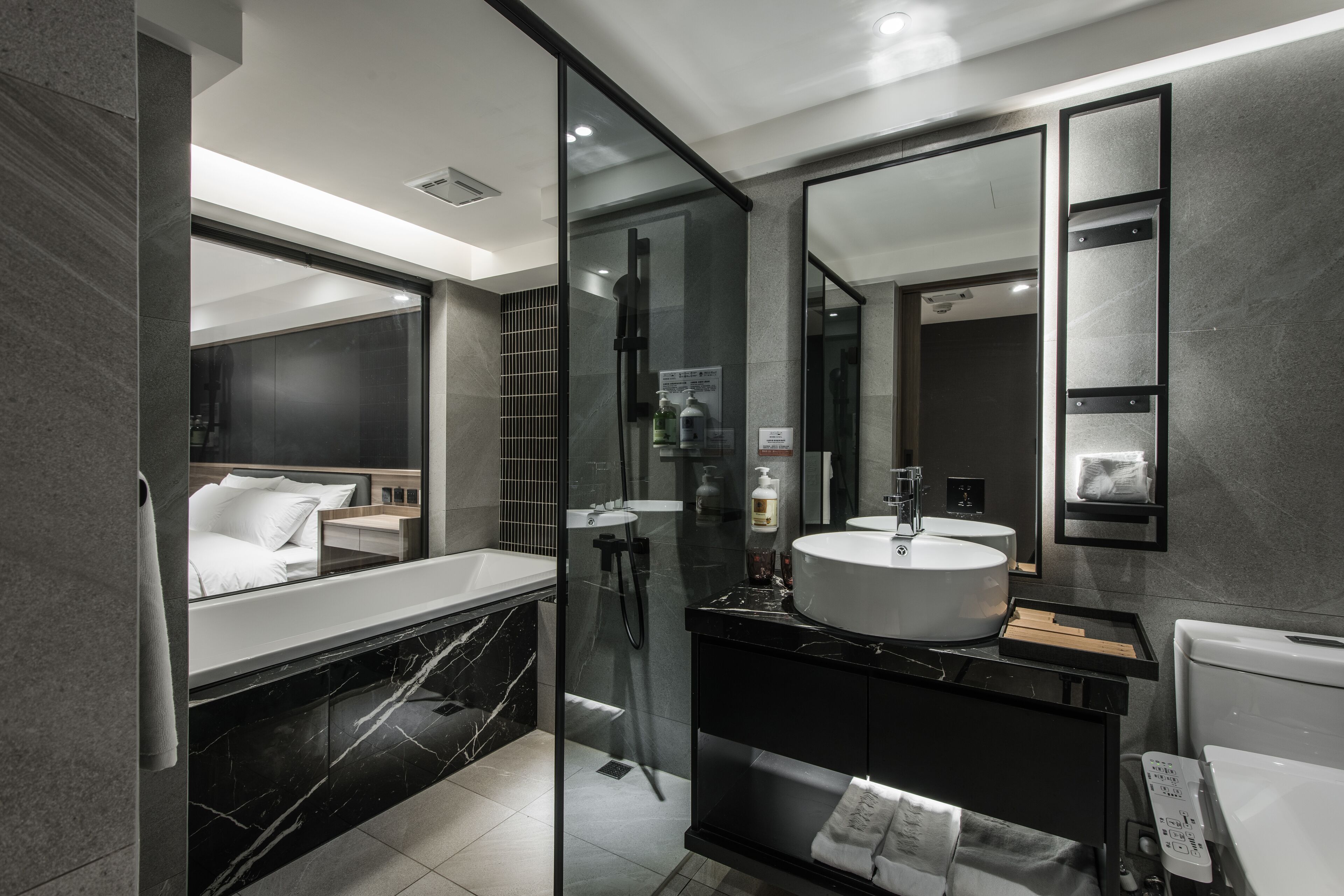 Un baño moderno con un espejo grande, una bañera y una zona de ducha separada.