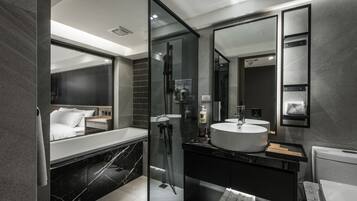 Un baño moderno con un espejo grande, una bañera y una zona de ducha separada.