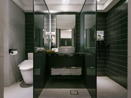 Egy modern fürőszoba üveg válaszfallal, WC-vel, mosdókagylóval és tükörrel.