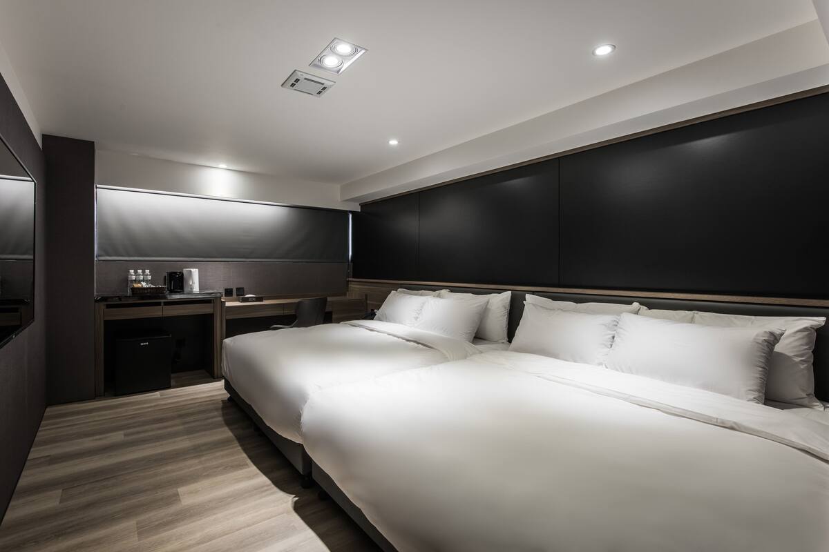 A modern hotel room with a large bed, a desk, and a chair.