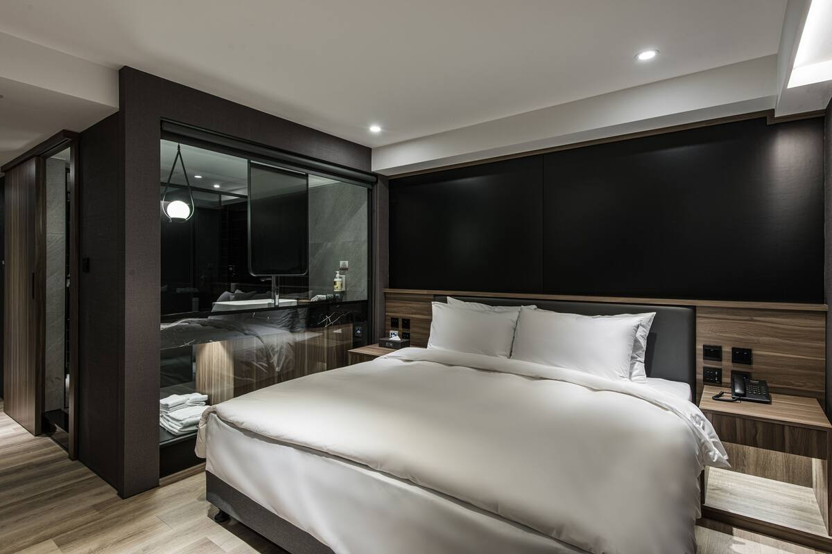 A modern bedroom with a large bed, a walk-in closet, and a large mirror.